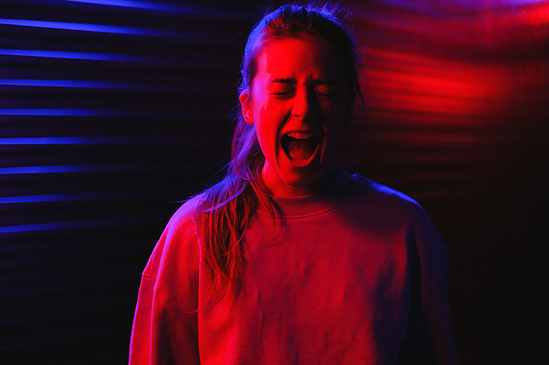 A woman screams in a dramatically lit scene with red and blue hues.